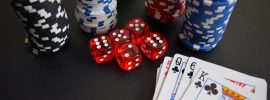 Playing cards alongside poker chips and red casino dice on a felt table